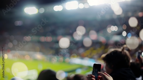 Spectators capture the game with smartphones at a brightly lit stadium event