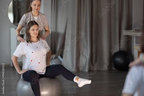 Pregnant Woman Practicing Prenatal Exercise on Stability Ball With Physiotherapist in Maternity Clinic
