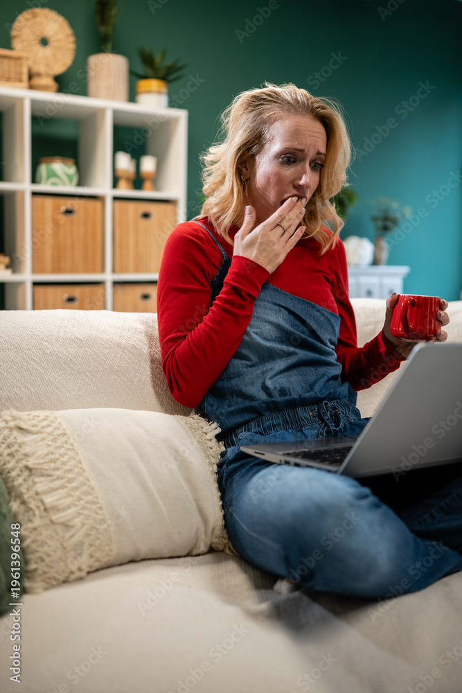 Obraz premium Woman experiencing shock while watching bad news on laptop
