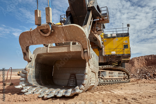 the colossal dipper of an electric rope shovel looms against a steel-grey sky, its serrated teeth and battle-worn steel shell radiating the unstoppable force of modern large-scale mining. 