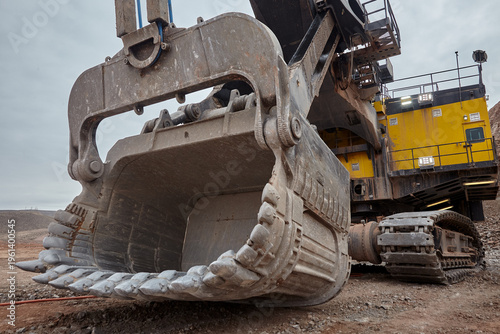 the colossal dipper of an electric rope shovel looms against a steel-grey sky, its serrated teeth and battle-worn steel shell radiating the unstoppable force of modern large-scale mining. 