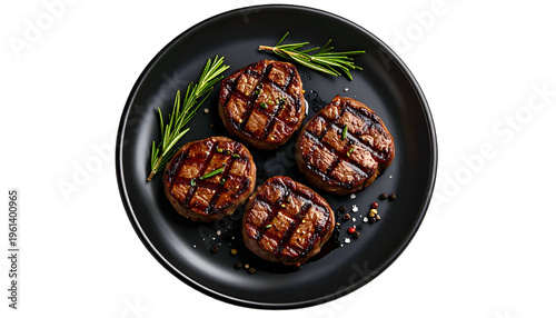 Four grilled medallions on a black plate, garnished with rosemary and peppercorns