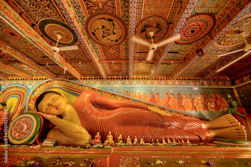 A reclining Buddha statue shows intricate details and designs within Isurumuniya Rajamaha Viharaya temple