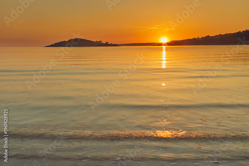 Sunset observed from Bantham showing Burgh Island and calm waters off the south coast of Devon in Great Britain