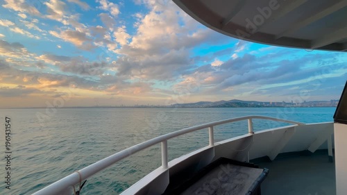Wide angle view from passenger ferry sailing across the Marmara Sea and approaching Istanbul at sunset with dramatic clouds and sea surface. city skyline, travel and tourism concept