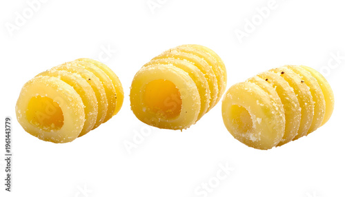 Close-up of three cylindrical, ridged pasta shapes, textured and isolated on black