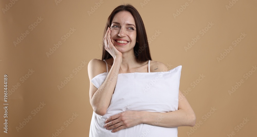 Fototapeta premium Beautiful woman with pillow on beige background