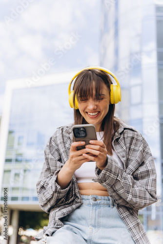 Young woman enjoying music and connection with a smartphone and yellow headphones in a city setting