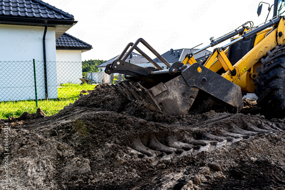 Fototapeta premium Backhoe loader bucket moving soil on construction site