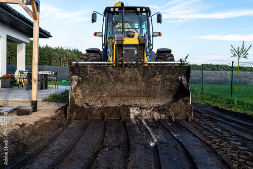 Yellow excavator front loader grading ground leveling for construction
