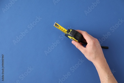 Quadro su tela Man with measuring tape on blue background, top view