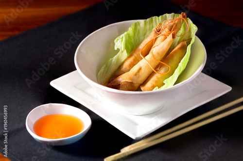 Asian Crispy Shrimp Rolls in a white blow with dipping sauce; copy space 