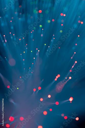Abstract fiber optic light explosion with colorful bokeh dots on dark teal background
