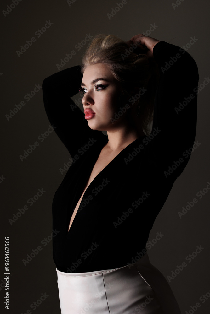 Fototapeta premium Model poses elegantly with hands in hair against dark background