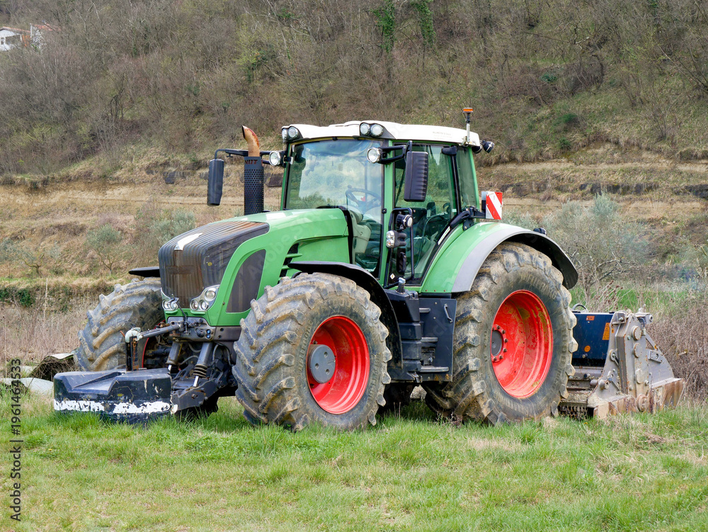Obraz premium Modern green tractor on field, agricultural machinery in rural countryside