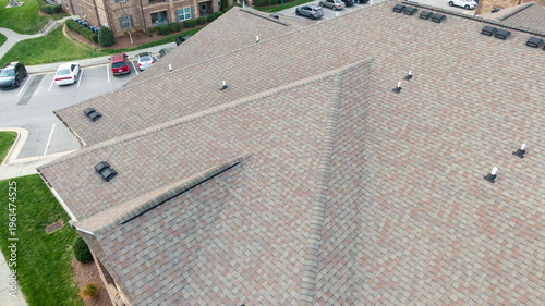 Aerial drone view of a modern apartment building featuring a new charcoal grey asphalt shingle roof.