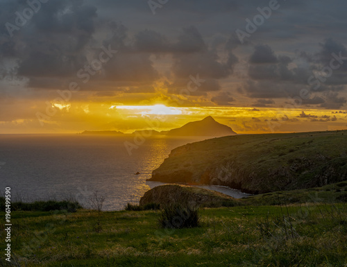 Sun rising in the cloudy sky over Anacapa Island as the shoreline begins to glow from dawns light.
