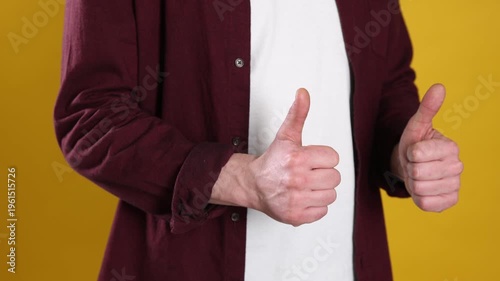 Man showing thumbs up on yellow background, closeup