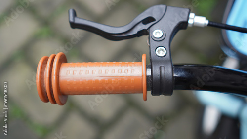 Close up of a brown rubber handlebar grip on a small child's bicycle and black brakes