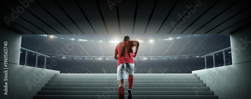 Rear view of a football player walking out of the tunnel onto the pitch. An imaginary soccer stadium is modelled and rendered.