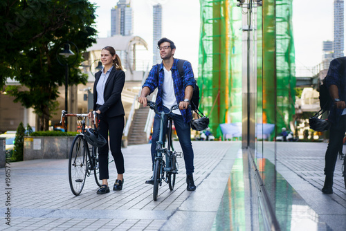 Business people with bicycles walking in urban environment.