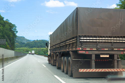 Large cargo truck driving on a highway in Brazil, representing logistics, transportation and supply chain in a natural landscape.