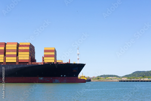 Large container ship with stacked containers at Port of Santos, Brazil, representing global trade and maritime logistics under clear blue sky.
