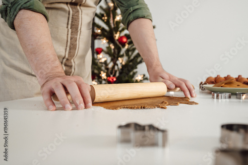 Side view on man rolling out the dough preparing cookies for chrismas