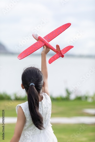 A little Chinese girl playing with a toy airplane in the park