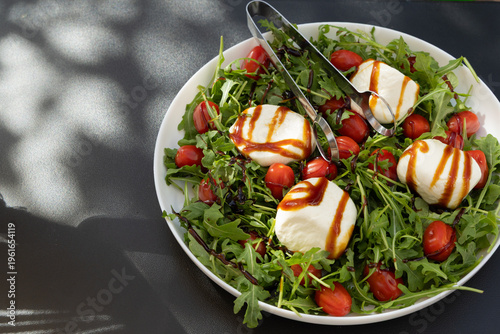 Fresh Salad With Mozzarella Cheese and Cherry Tomatoes Served on a White Plate During Lunchtime on a Sunny Day