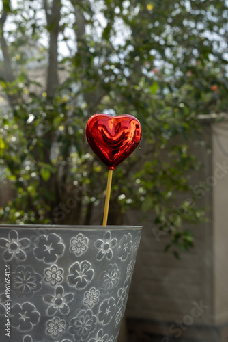 Heart-shaped Decoration Sticks out From a Gray Pot in a Garden on a Sunny Day