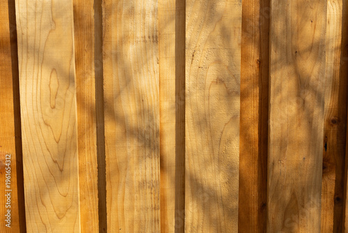 Wooden Planks Show Natural Grain Pattern With Shadows on Surface in Outdoor Setting During Daylight