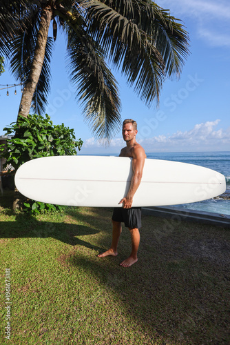 Beachside Surfer Ready For Ride. Person Carrying Surfboard Along Coast During Early Morning Hours
