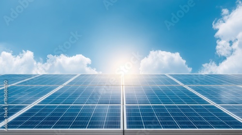 Expansive Solar Panels Absorbing Sunlight Under Clear Blue Sky with Soft Clouds in the Background, Representing Renewable Energy and Sustainability