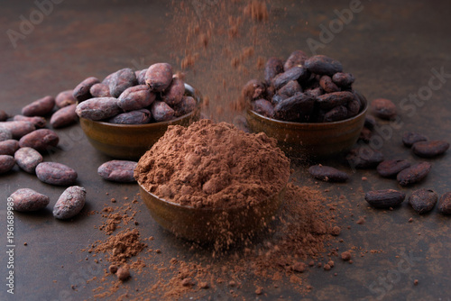 Cocoa beans and a pile of cocoa powder in wooden bowls on a stone table
