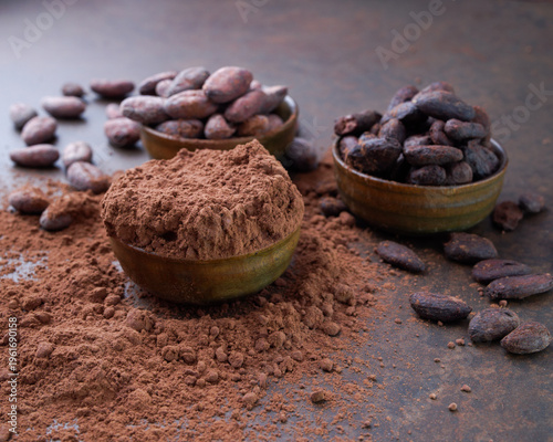 Cocoa beans and a pile of cocoa powder in wooden bowls on a stone table