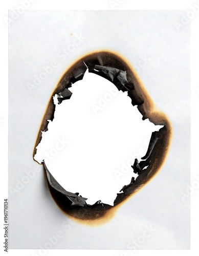 Close-up of burnt hole in white paper, edges charred and jagged against a white background