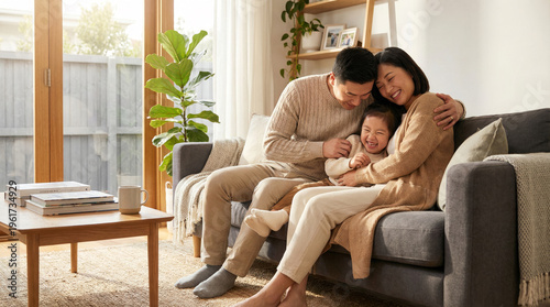 Happy Asian Family Playing on Sofa, Father Tickling Daughter in Sunlit Modern Living Room