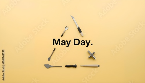 A creative arrangement of tools forming a triangle with the words May Day in the center on a yellow background