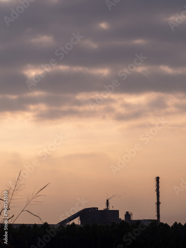 Factories and tall smokestacks stand alone amidst agricultural and wasteland areas