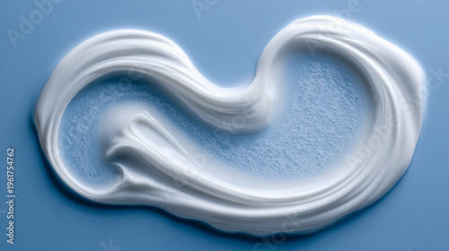 White creamy lotion or moisturizer spread artistically on a light blue surface with visible bubbles inside the texture.