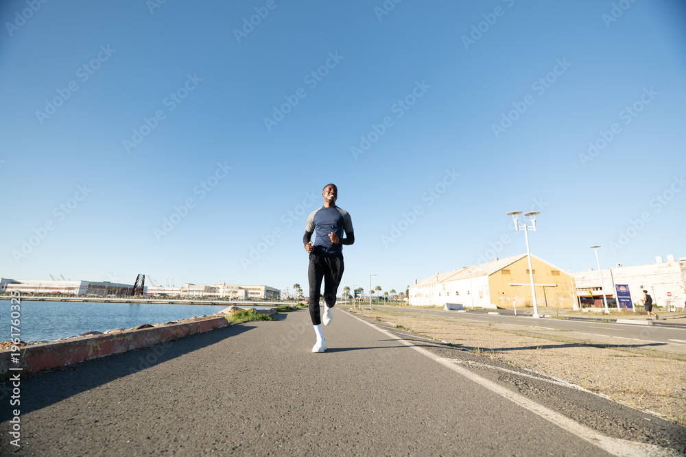 Obraz premium Black man running on urban path near the water