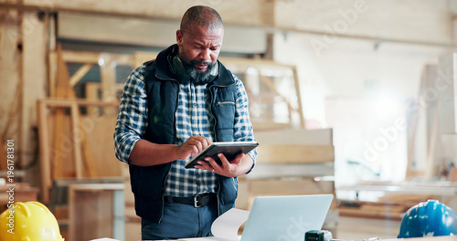 Fotografi Black man, carpenter and typing with tablet at factory, notes and manufacturing report at industrial plant