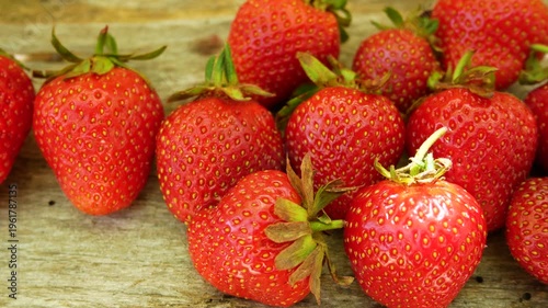 Ripe red juicy strawberries on a wooden table in bright summer sunlight. Concept of organic farming, seasonal harvest, and natural sweet dessert. Fresh berries, healthy nutrition, and summer lifestyle