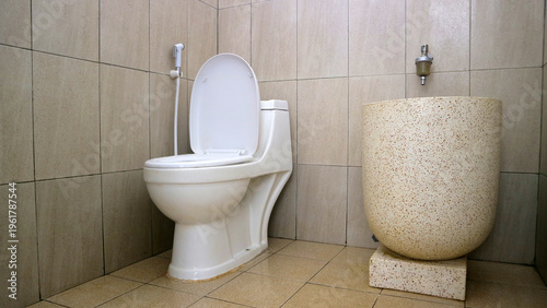 Foto Modern tiled bathroom with open toilet, bidet sprayer, and large stone vessel sink or basin, clean minimalist interior