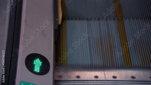 Close view of escalator lights showing active status at a busy station during the morning rush hour with commuters nearby