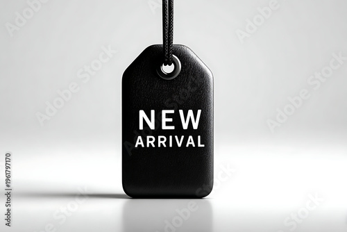 A black tag with the words 'NEW ARRIVAL' printed on it, hanging from a string against a plain background.