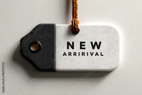 A close-up of a black and white tag with the words 'NEW ARRIVAL' on it, hanging from a brown rope against a plain background.