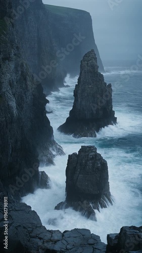 Stormy waves crash against rugged rocky cliffs and sea stacks on a gloomy day by the ocean