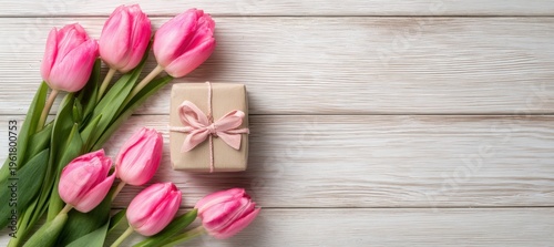 Pink tulips with small gift box on light wooden table background with apple wood texture and copy space